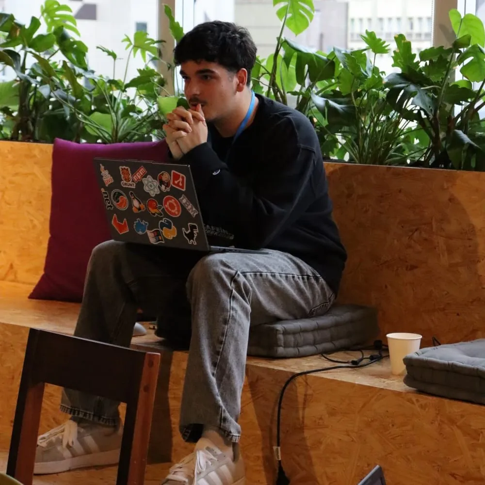 Henrique Bueno sentado com o notebook cheio de adesivos