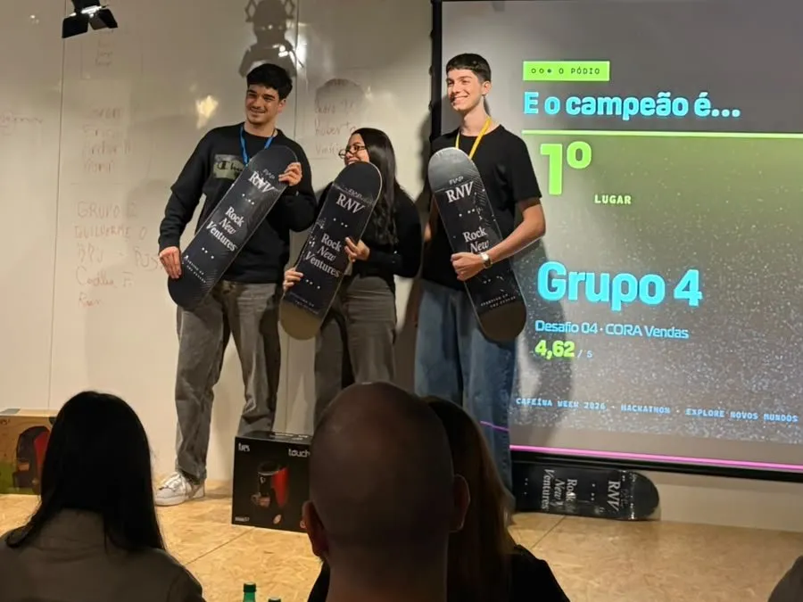 Henrique e o time no palco segurando os shapes de skate do prêmio, com o telão anunciando o Grupo 4 em primeiro lugar